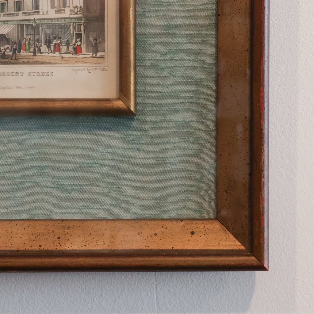 Close-up of a framed vintage print on a textured wall.