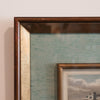 Close-up of a framed artwork with a textured wall background