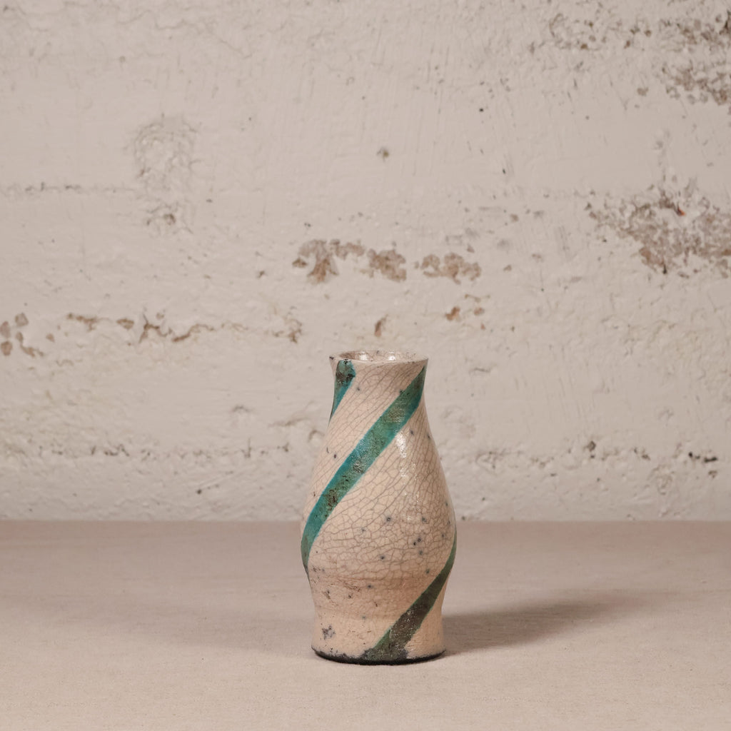 Ceramic vase with green stripes on a textured surface and background