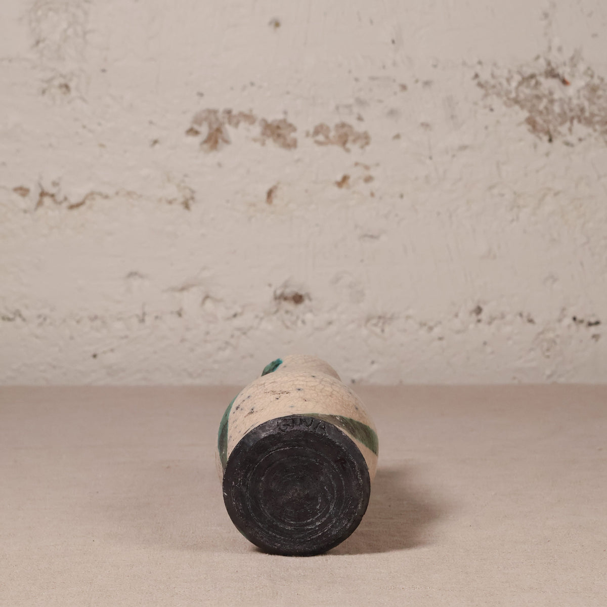 small ceramic vase against a textured beige wall