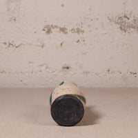 small ceramic vase against a textured beige wall