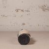 small ceramic vase against a textured beige wall