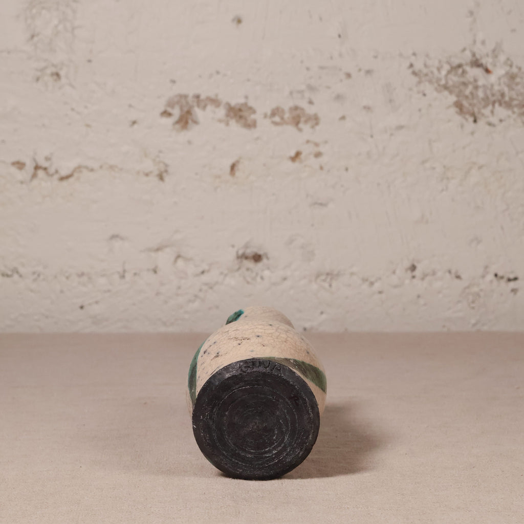 small ceramic vase against a textured beige wall