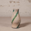 Ceramic vase with green stripe on a beige surface and textured wall background
