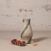 Ceramic vase with green stripe on a textured surface with decorative elements