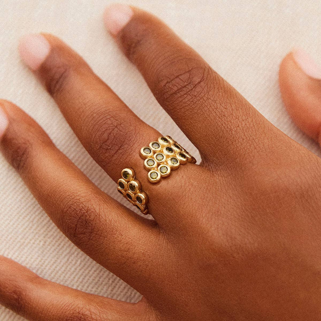 Gold ring with green gemstones on a hand 