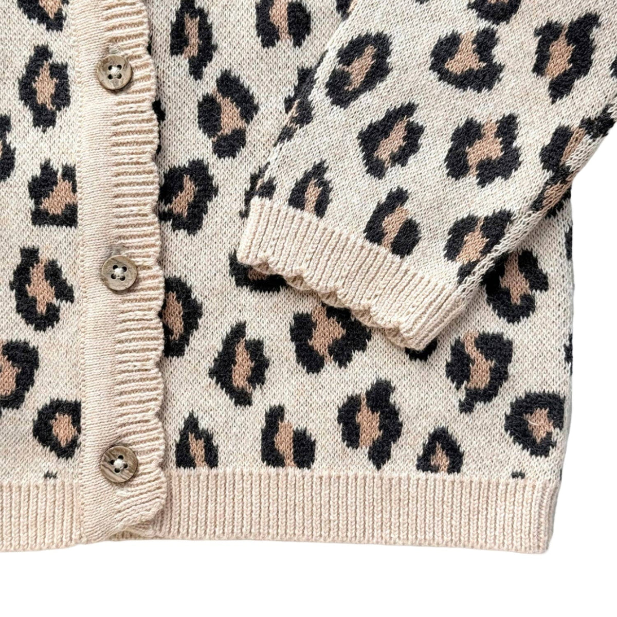 Close-up of a leopard print cardigan with beige buttons on a white background