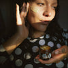 Woman applying a face mask with a jar of cream in a dimly lit room
