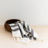 Striped towel draped over a wooden bowl on a light surface with a white background