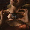 Woman holding a jar of cream against a dark background