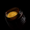 Open jar of face paste with visible product inside on a black background