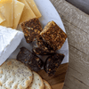 Assorted cheese, fig and walnut, bites, and crackers on a wooden board.