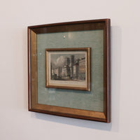 Framed artwork of a cityscape on a light gray wall