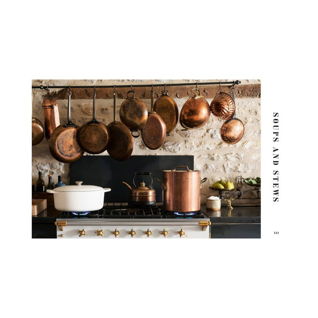 Copper pots and pans hanging above a stove in a kitchen.
