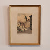Framed artwork of a city street scene on a beige wall