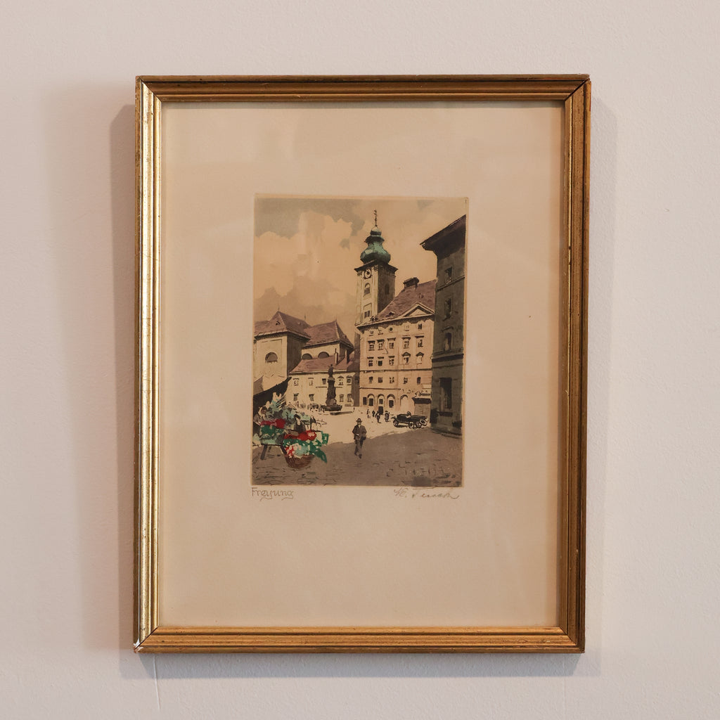 Framed artwork of a city street scene on a beige wall