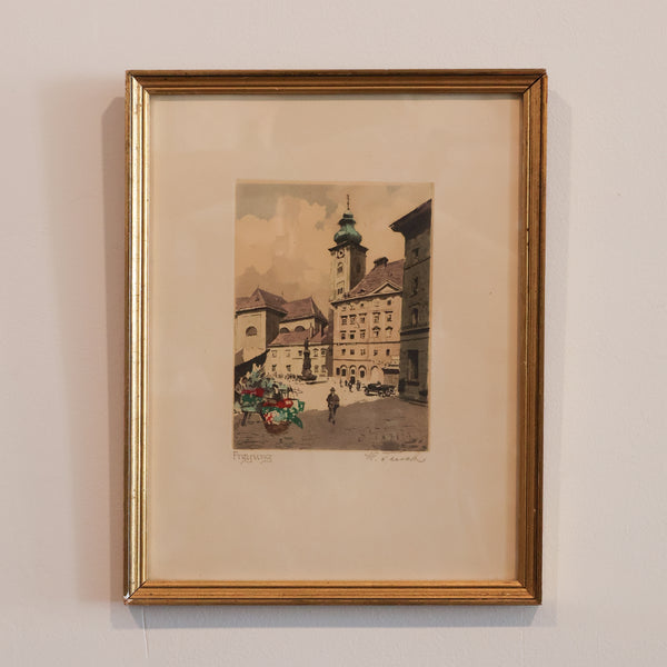 Framed artwork of a city street scene on a beige wall