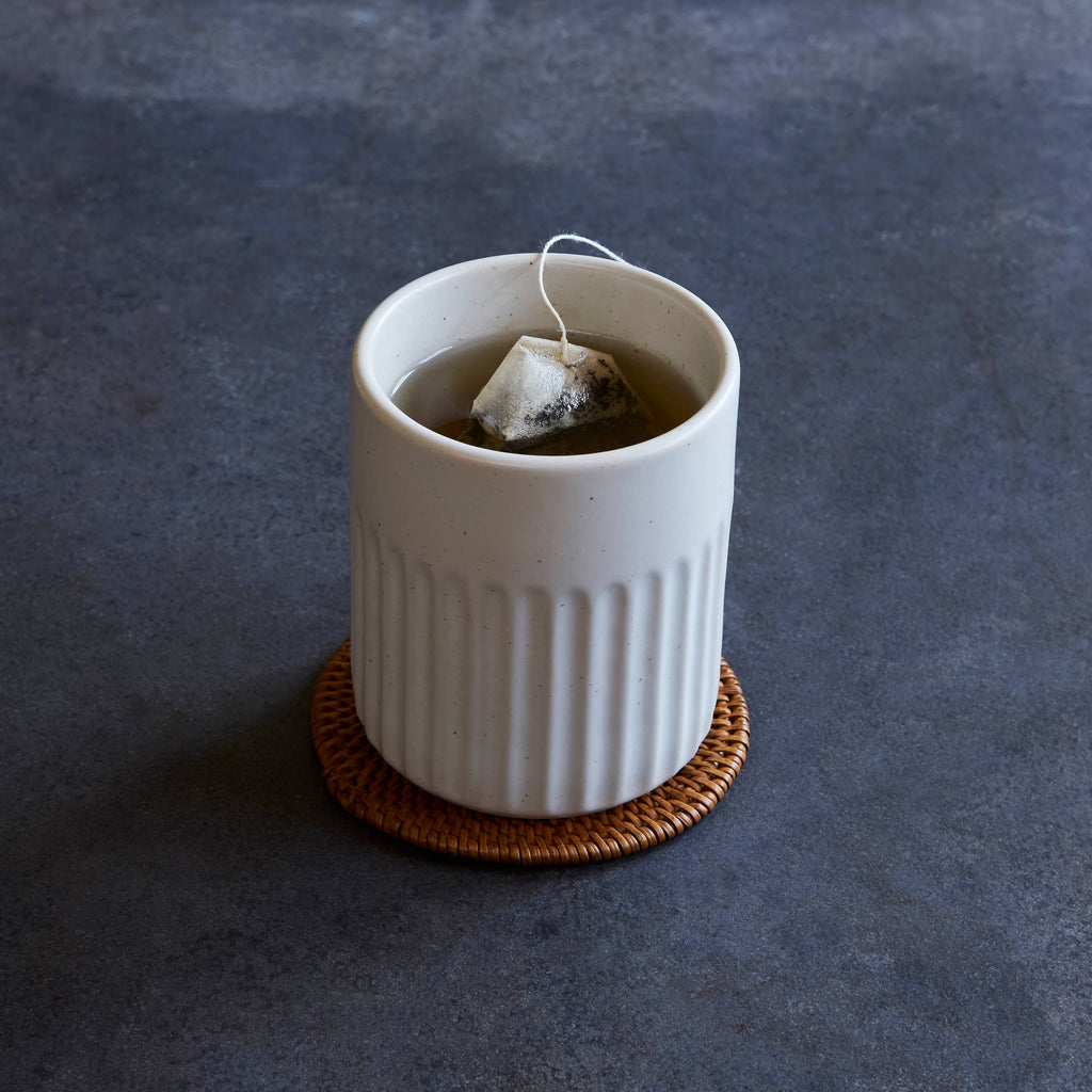 White ceramic mug with a tea bag on a dark gray background