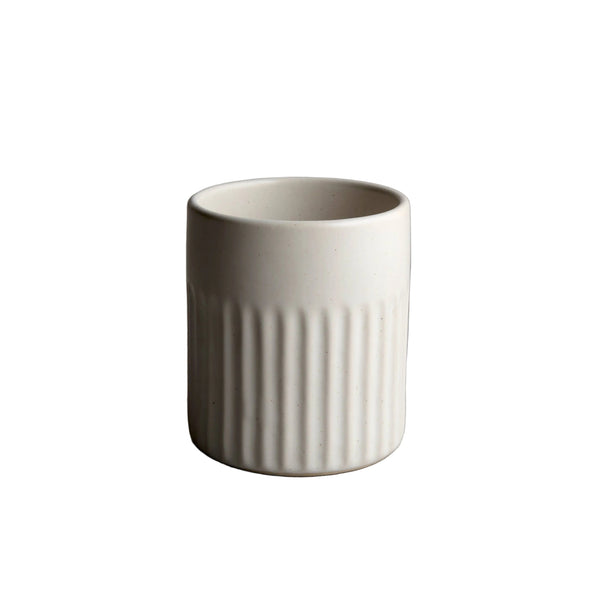 White ceramic cup with ribbed texture on a gray surface