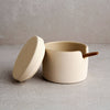 Beige ceramic pot with a lid on a light gray surface