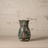 Decorative ceramic pitcher with green and black patterns on a textured surface.
