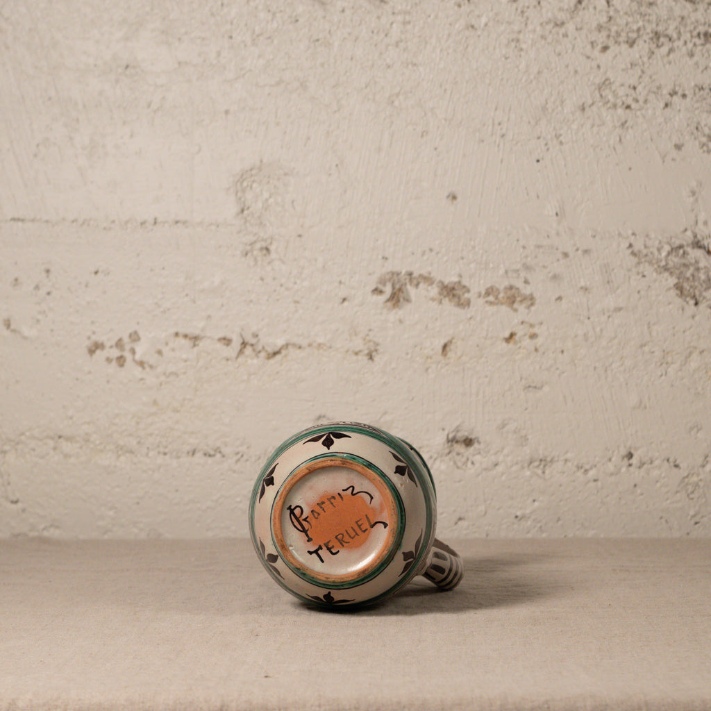 Ceramic pitcher bottom with decorative design on a textured surface