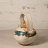 Ceramic teapot with decorative handles on a textured surface