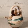 Ceramic teapot with decorative patterns on a textured surface
