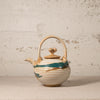 Ceramic teapot with decorative patterns on a textured surface