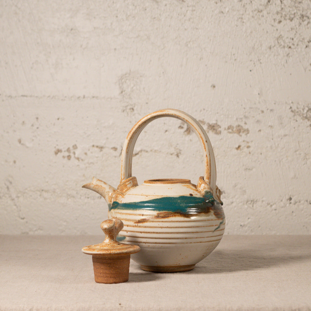 Ceramic teapot with decorative patterns on a textured surface