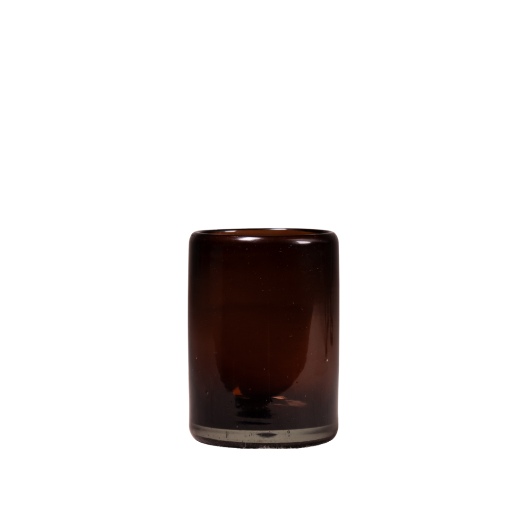A small cylindrical amber glass tumbler with a thick base, shown against a plain white background.