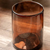 Brown glass tumbler with a liquid inside on a wooden surface