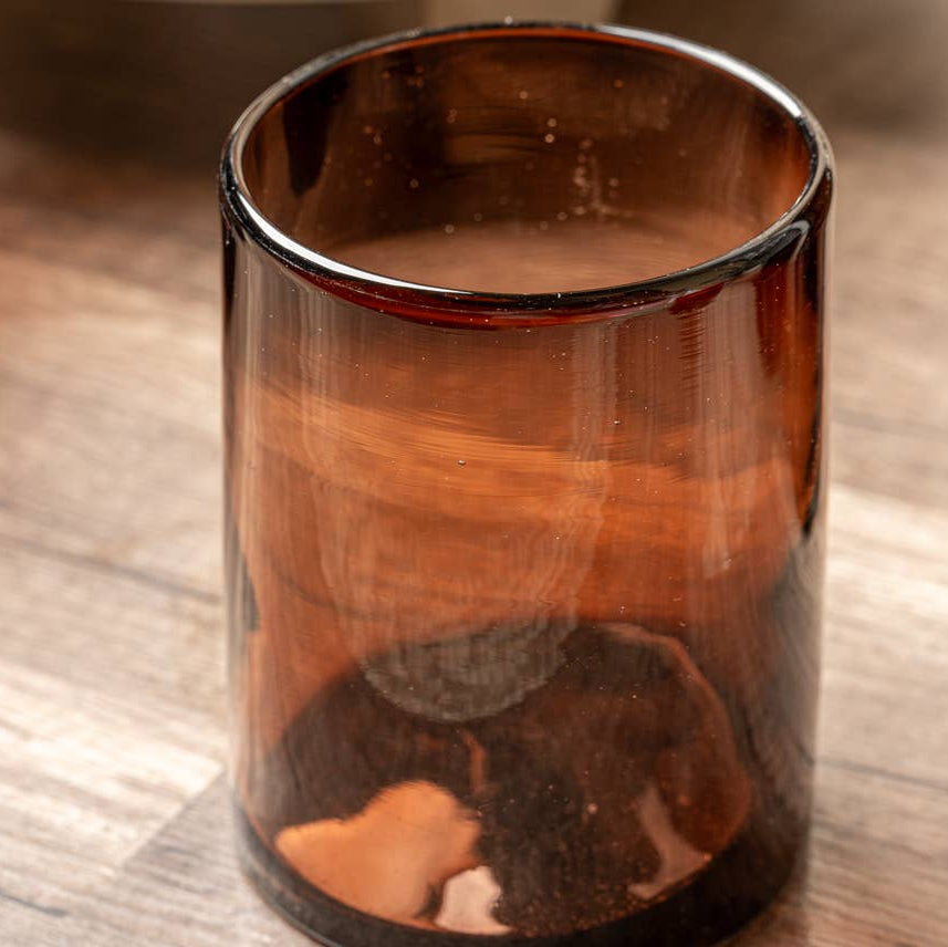 Brown glass tumbler with a liquid inside on a wooden surface