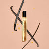 Bottle of 'Dirty Vanilla' with vanilla beans on a beige background