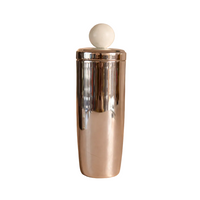 Silver cocktail shaker with a white ball on a beige background