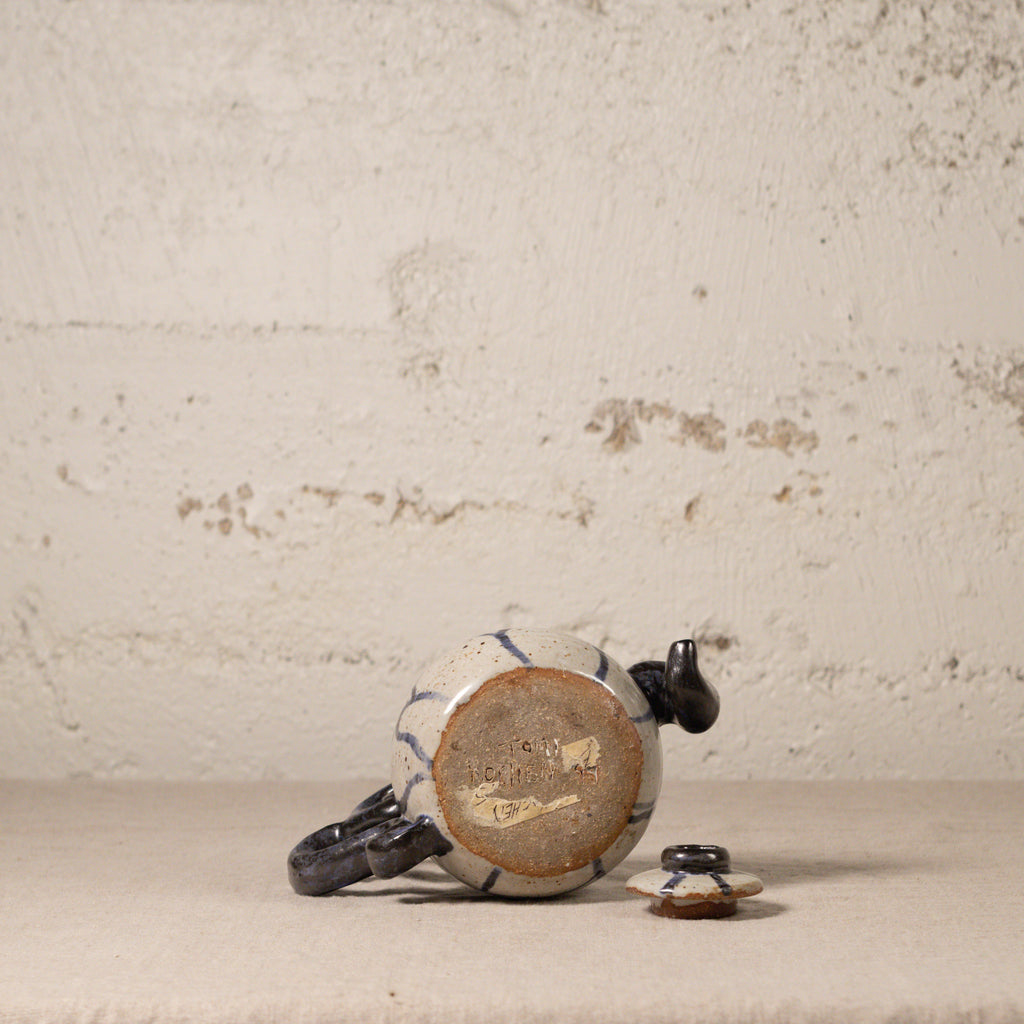 Ceramic teapot with decorative patterns on a textured surface
