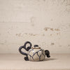 Ceramic teapot with indigo and white design on a textured beige background