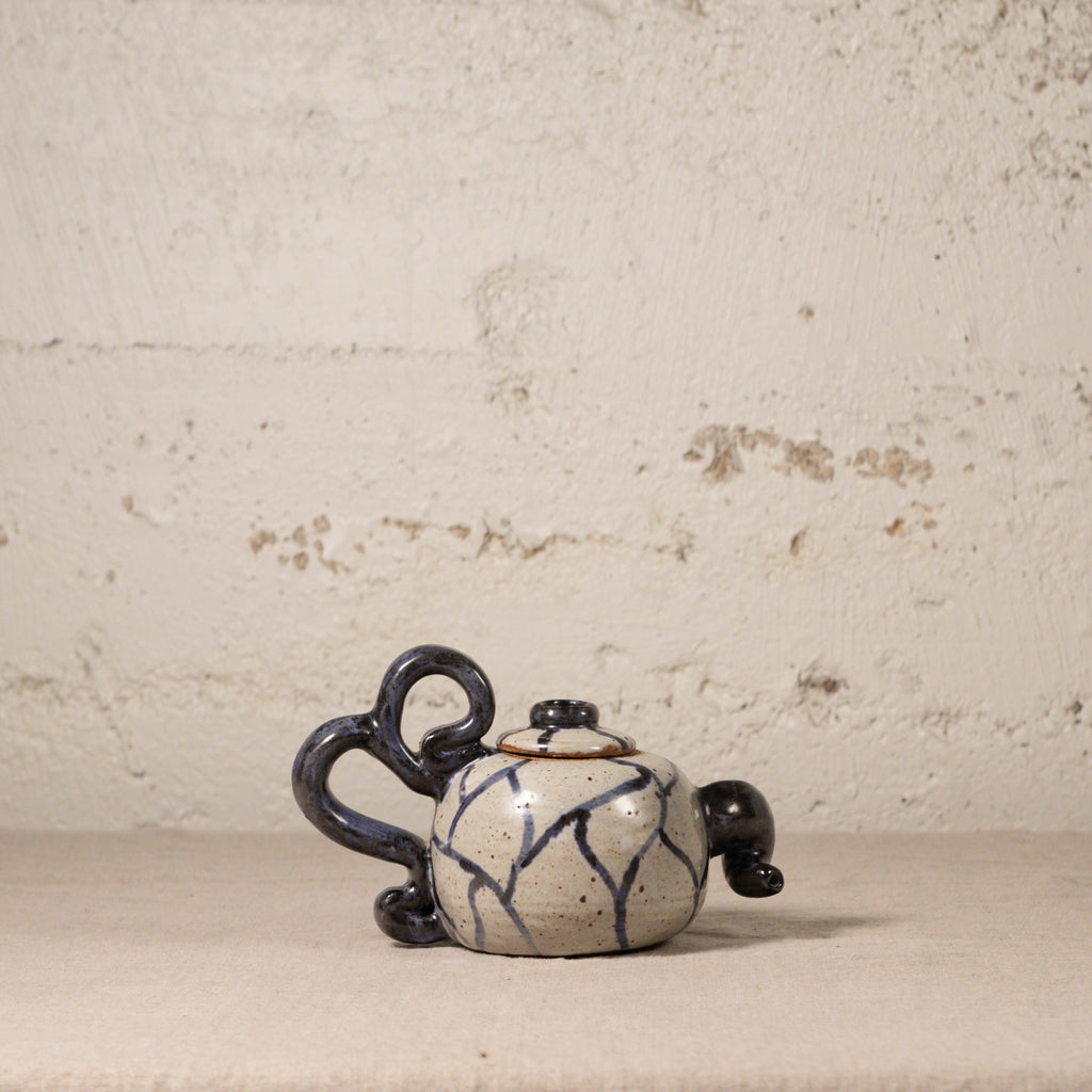 Ceramic teapot with indigo and white design on a textured beige background