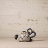 Ceramic teapot with blue patterns on a textured beige background