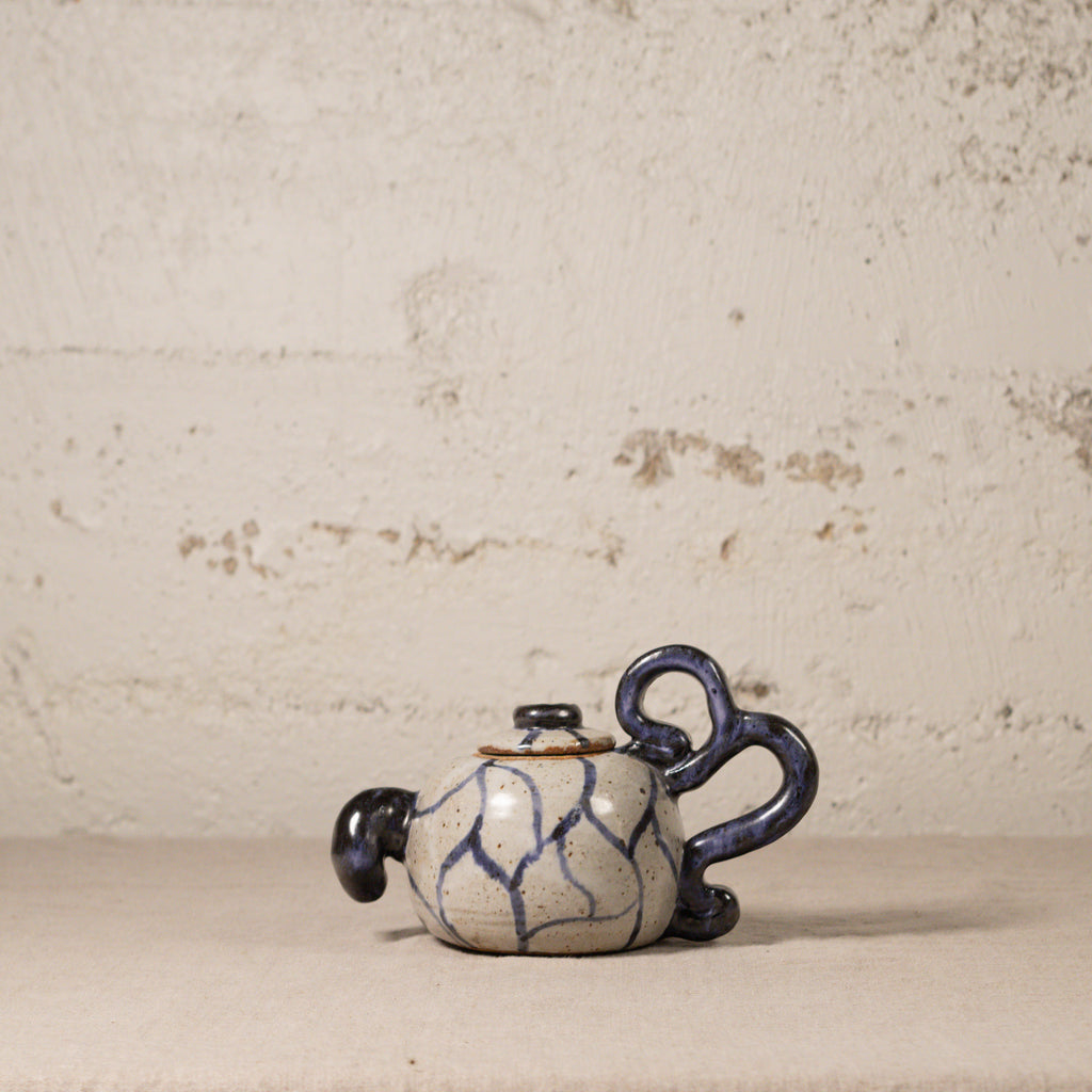 Ceramic teapot with blue patterns on a textured beige background