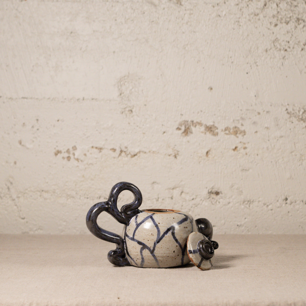 Ceramic teapot with blue patterns on a textured beige background