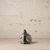 Small ceramic teapot with a indigo handle on a textured beige surface