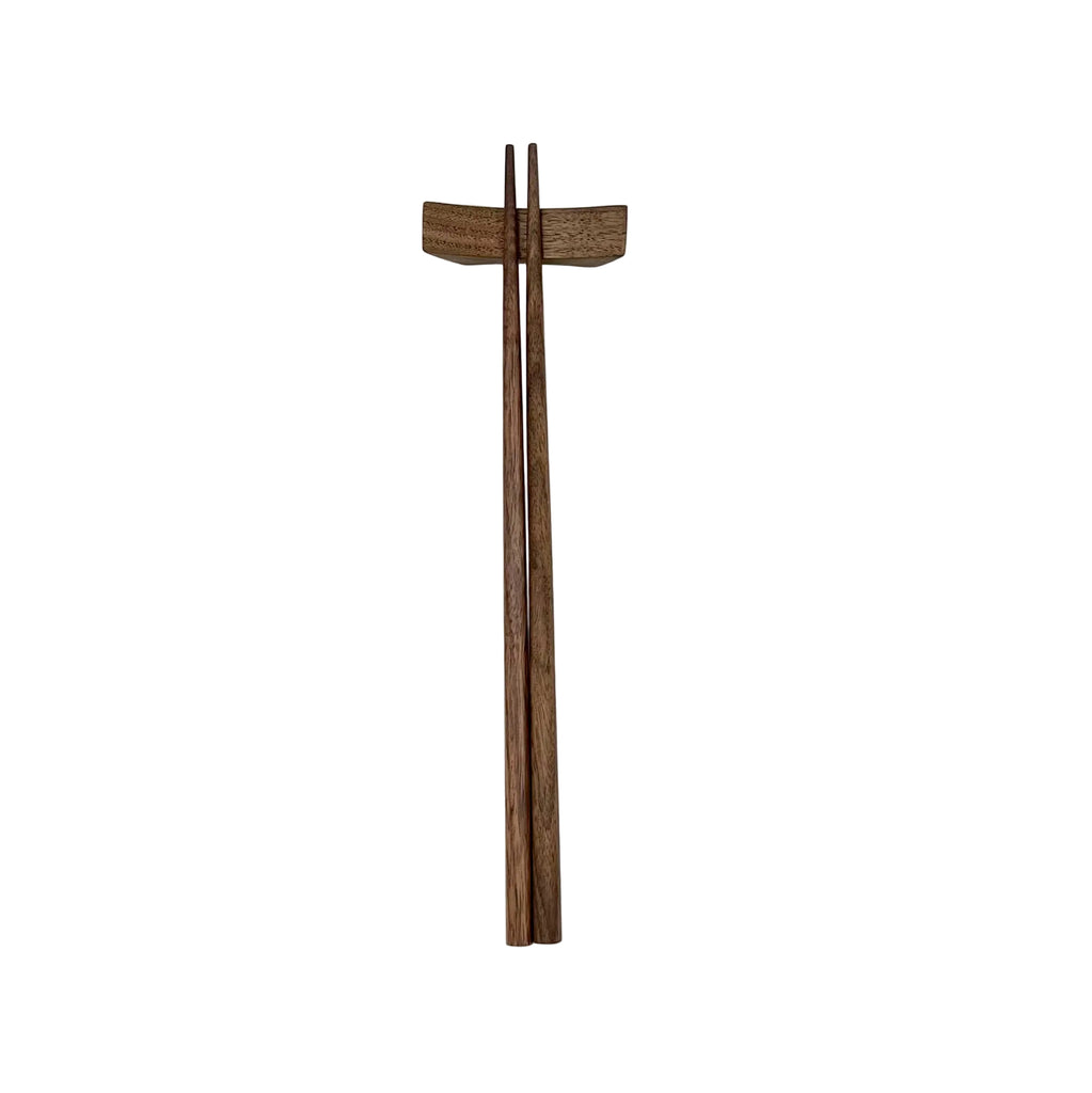 Wooden chopsticks and wooden rest on a white surface