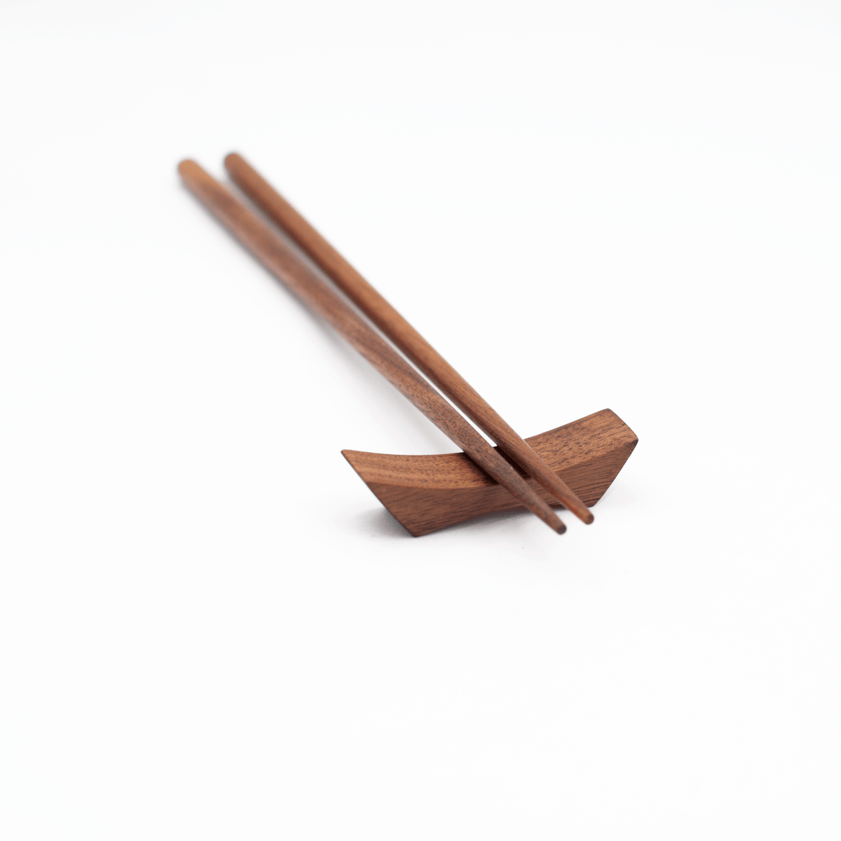 Wooden chopstick rest with two chopsticks on a white background