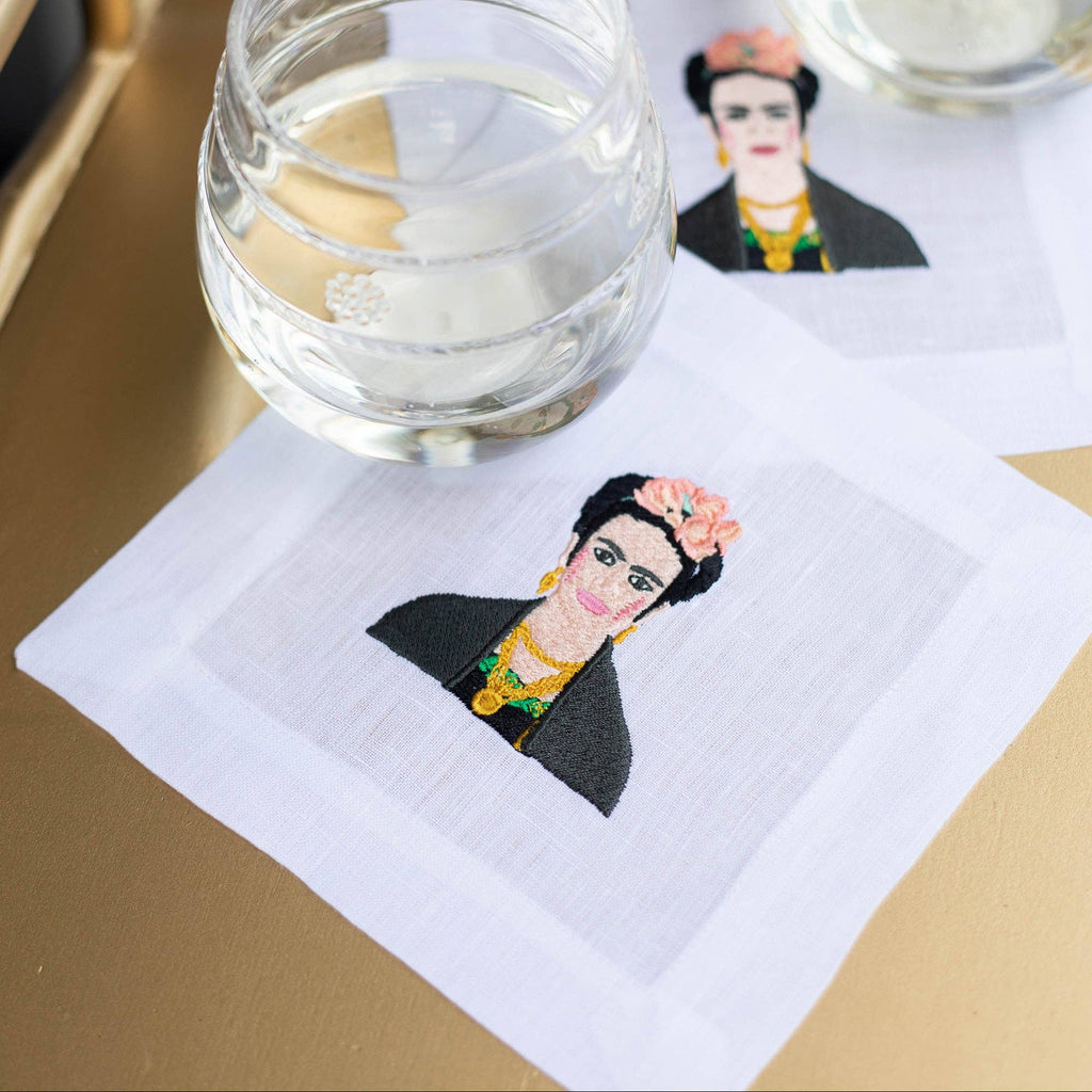 Two clear glasses on Frida Kahlo-themed napkins with a gold frame in the background.