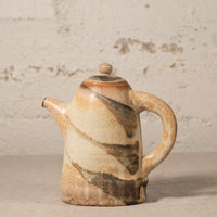 Ceramic teapot with marbled design on a textured surface