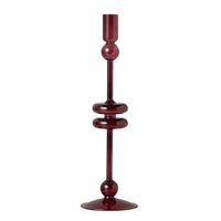 A tall, slender burgundy glass candlestick holder with decorative rounded sections, shown on a plain white background.