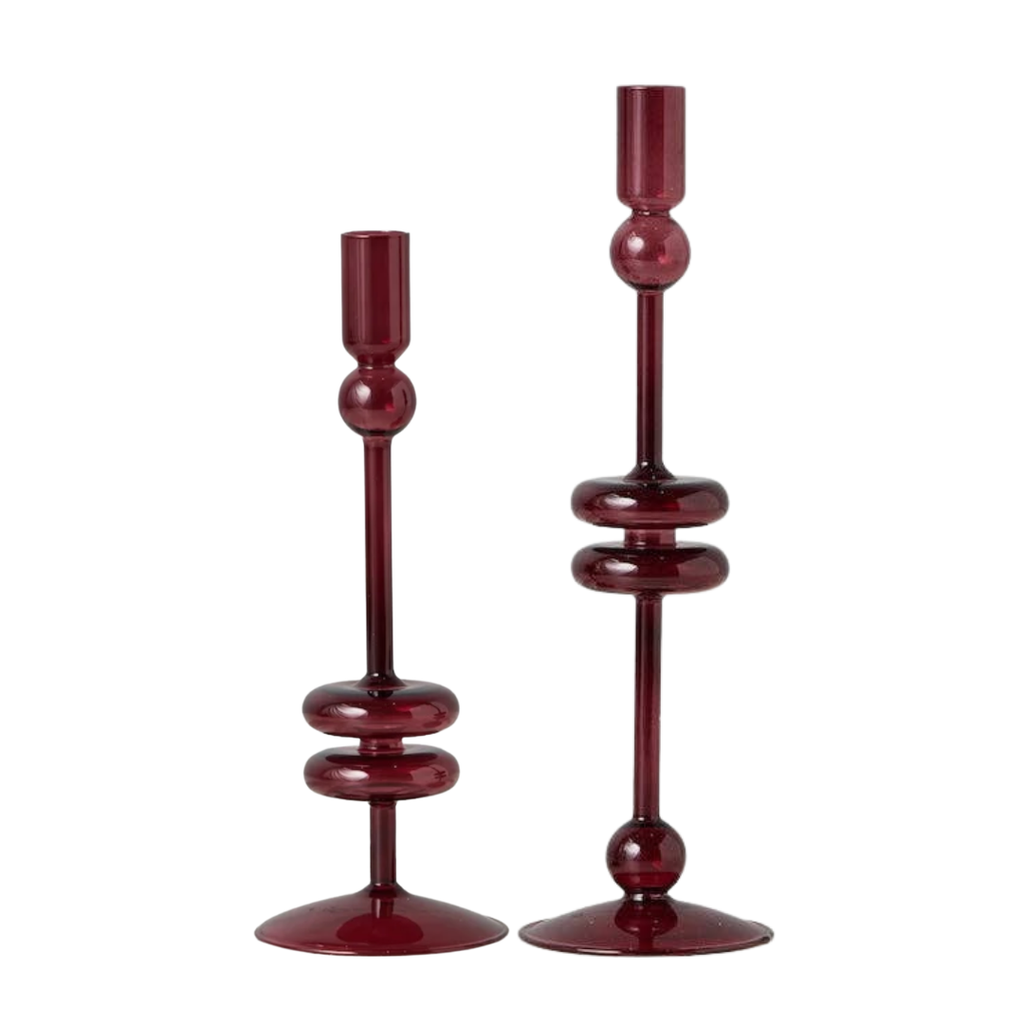 Two dark red glass candlesticks with unique stacked circular designs on their stems, set against a plain white background.