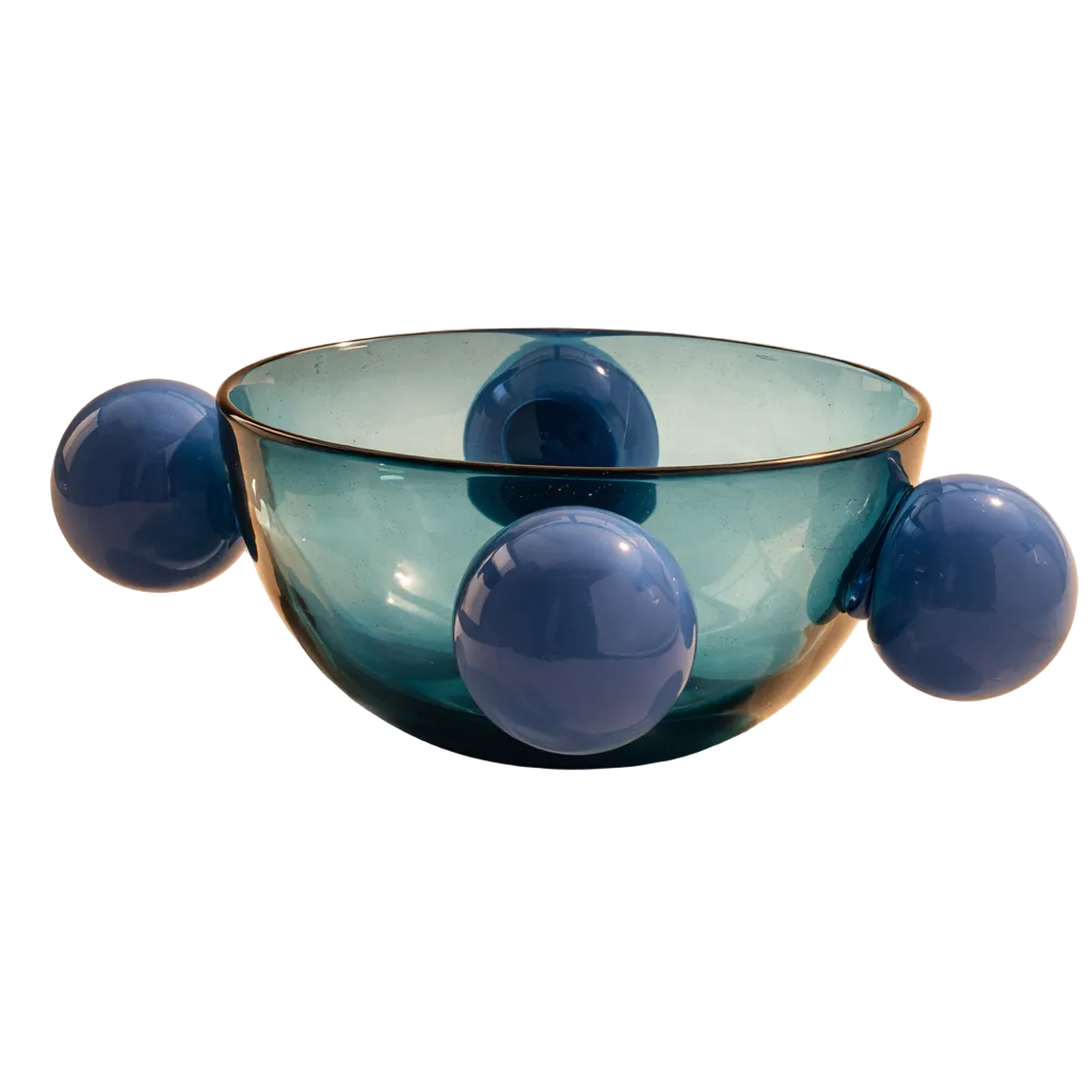 A translucent blue-green glass bowl with four rounded protruding spheres, photographed on a warm beige studio background with a soft shadow.
