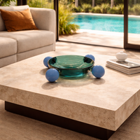 Modern living room with a coffee table, sofa, and view of a pool and garden.